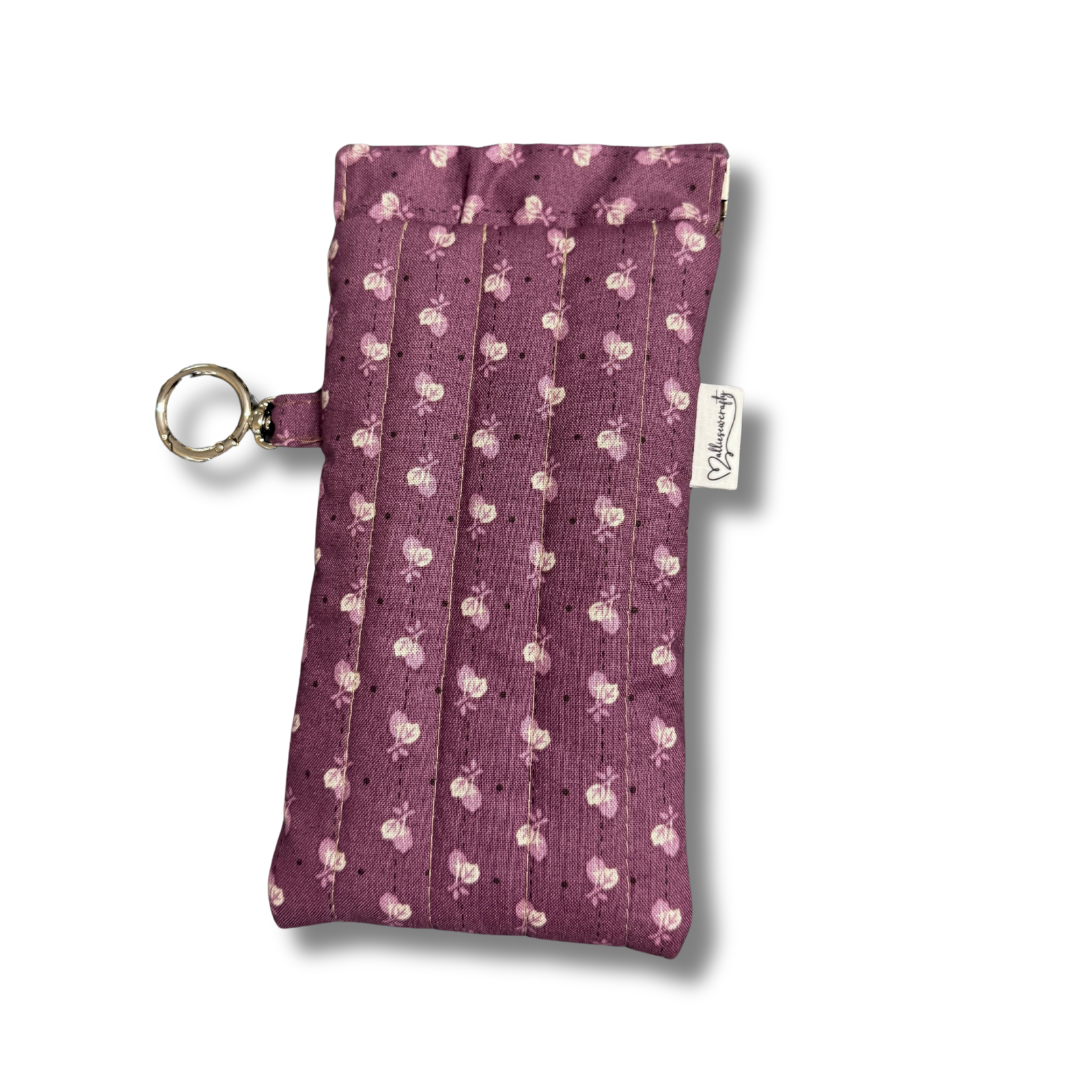 Small purple pouch with floral pattern and key ring on a white background