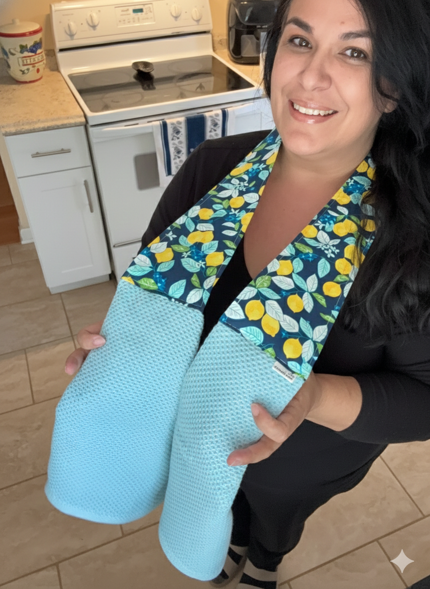 Person holding a set of blue oven mitts with a floral pattern in a kitchen.