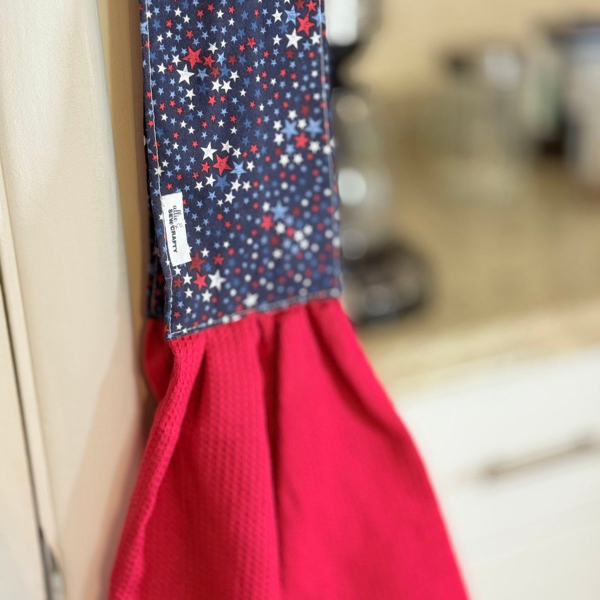 Red apron with a blue star pattern hanging on a hook.