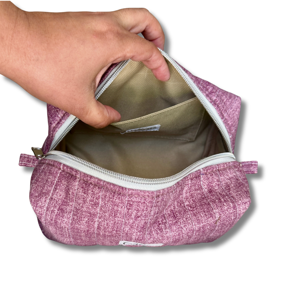A hand is shown opening a mauve textured zippered pouch to reveal a beige interior lining with a side pocket.