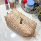 A beige quilted cosmetic pouch with a silver zipper and a small 'Allie.
