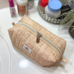 A beige quilted cosmetic pouch with a silver zipper and a small 'Allie.