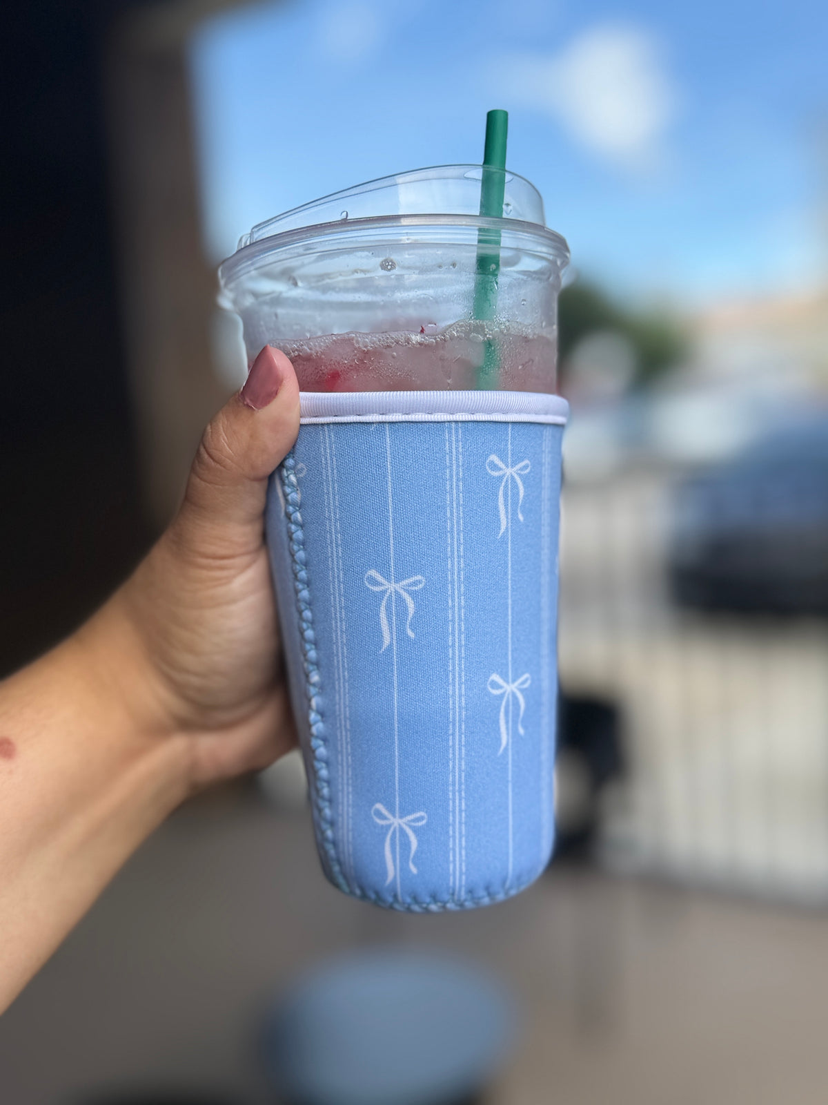 Cup sleeve with clear cup that's blue with white bows