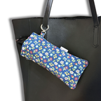Blue Wildflowers Meadow quilted Flexi Frame Pouch clipped to a black tote bag strap, holding sunglasses