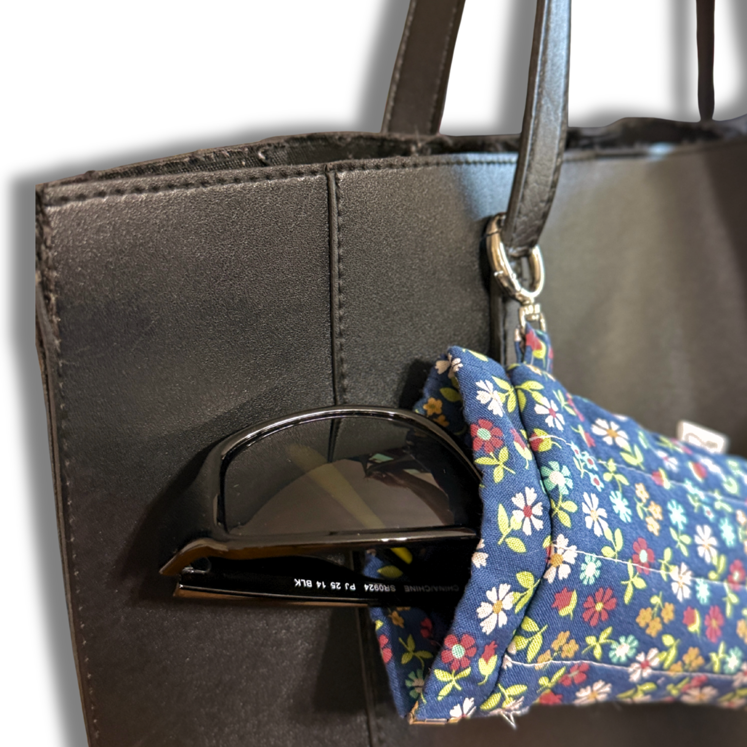 Blue Wildflowers Meadow quilted Flexi Frame Pouch clipped to a bag handle, close-up on the sunglasses tucked inside