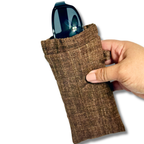 A hand holding a brown woven fabric sunglasses pouch with a pair of sunglasses inserted, shown against a plain white background.