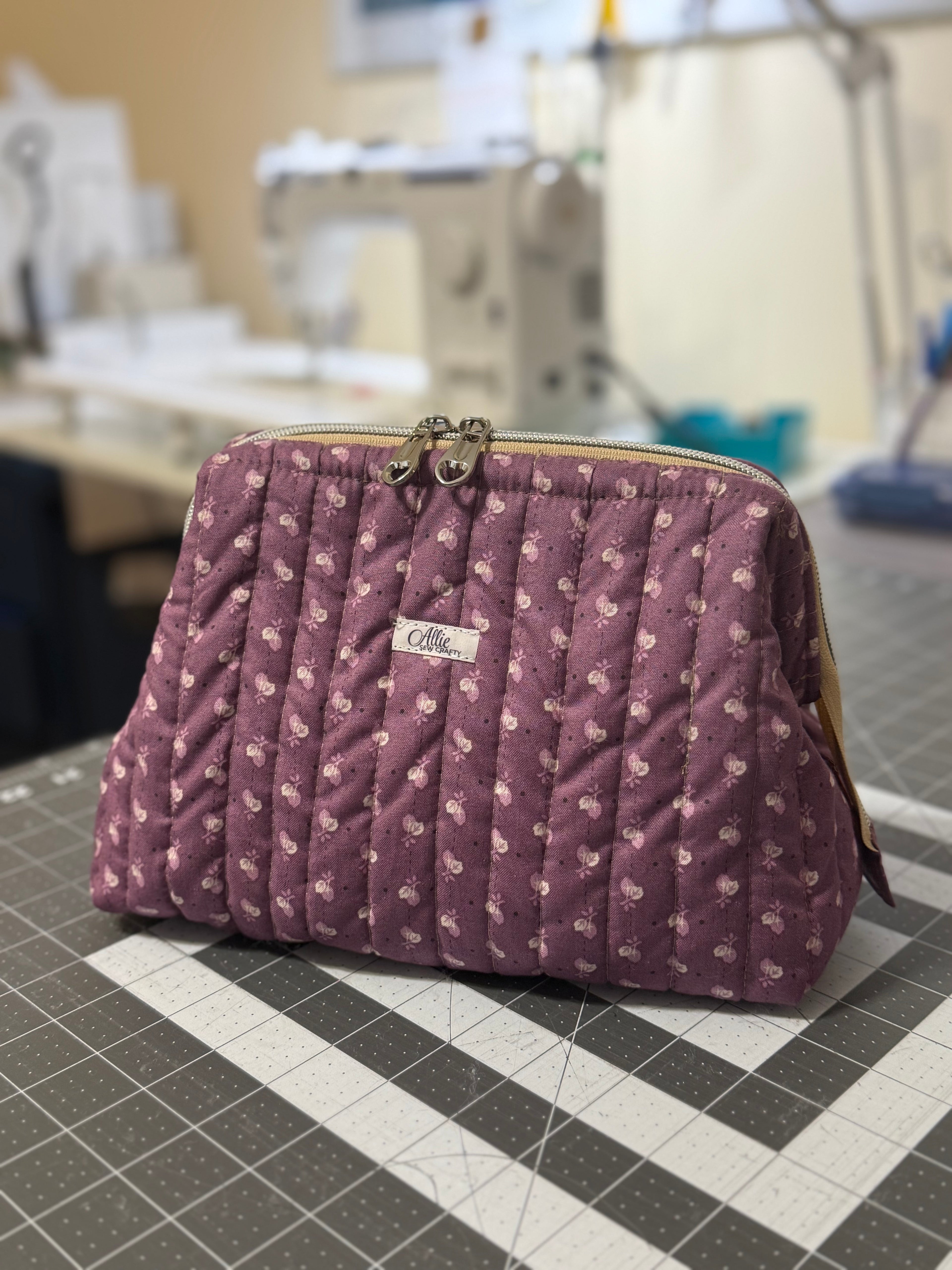 Purple quilted handbag with floral pattern on a checkered surface