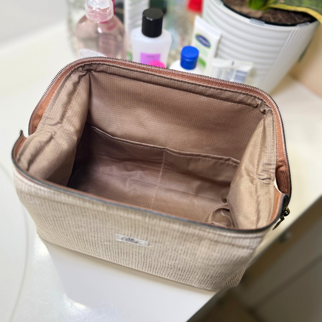 Beige toiletry bag on a bathroom counter with various items in the background