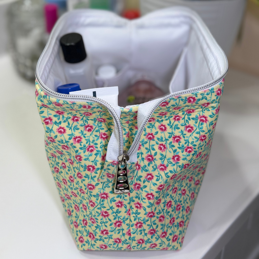 Floral-patterned pencil case with stationery items inside on a white surface