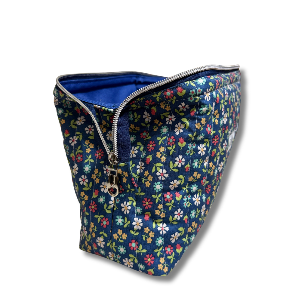 Side of full view pouch open with navy blue zipper and silver hardware, quilted pouch navy fabric with wildflower print