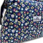 close up of quilting cotton fabric navy blue background with a colorful floral pattern of pink, yellow, white, and green flowers and Allie Sew Crafty in a white label.