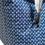 Close-up of a blue fabric bag or pouch with a repeating white cross pattern and a silver zipper.