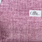A close-up of a textured fabric in a heathered pink and purple tone, featuring a white brand label that reads 'Allie Sew Crafty'.