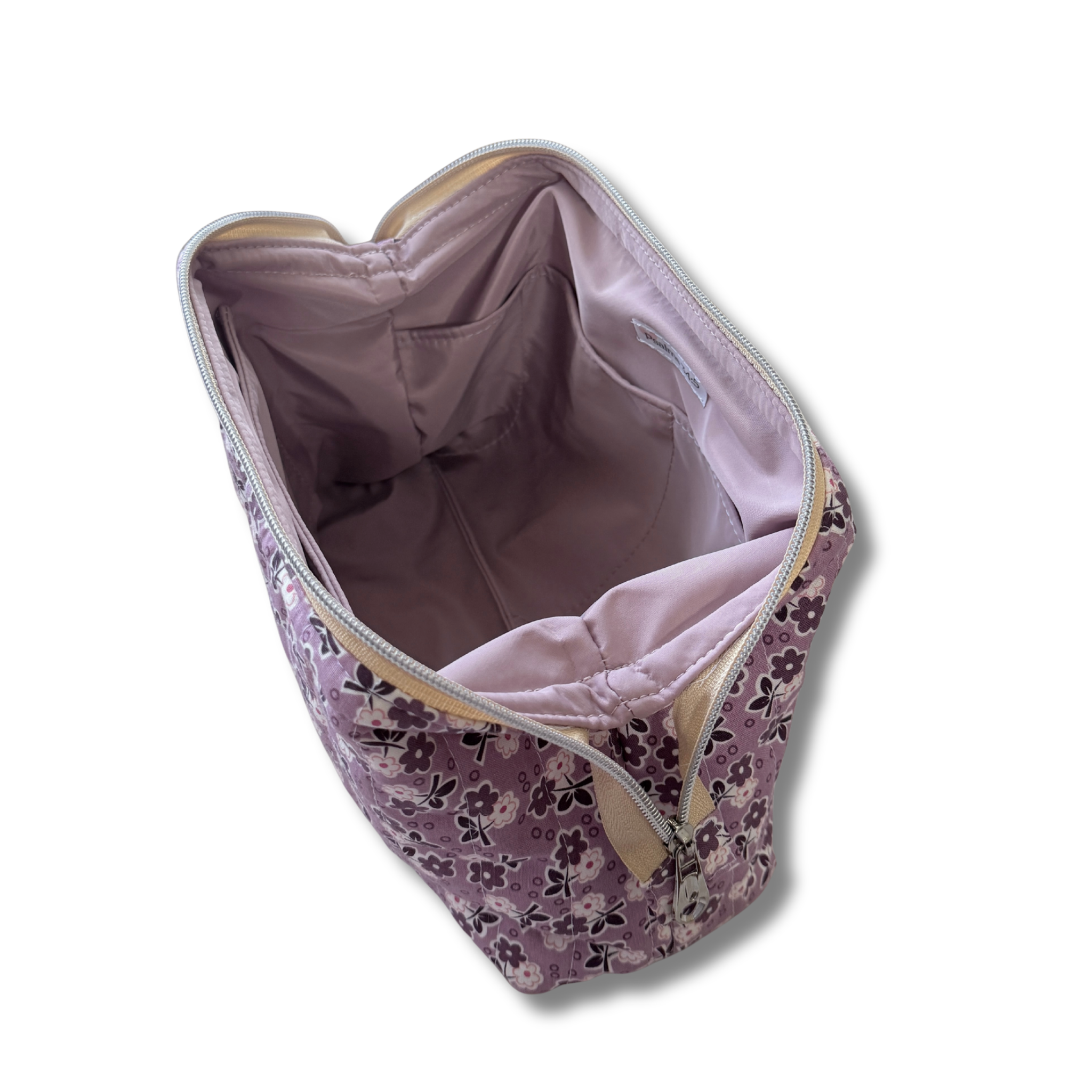 A lavender floral zippered cosmetic bag shown from an overhead angle, revealing a light purple interior lining and beige zipper trim, set against a plain white background.